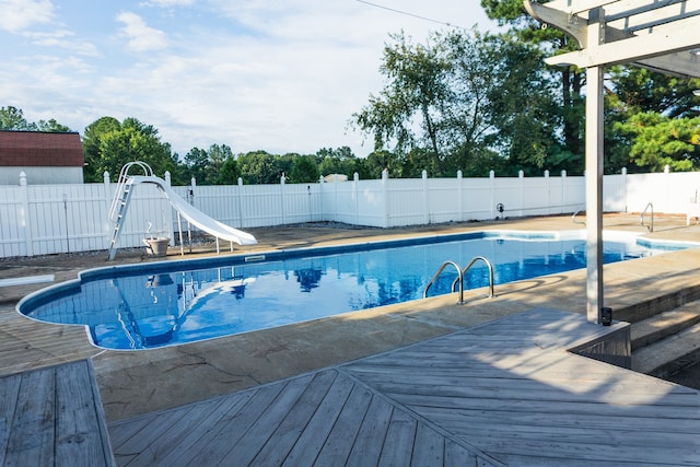 view of swimming pool featuring a water slide and a wooden deck