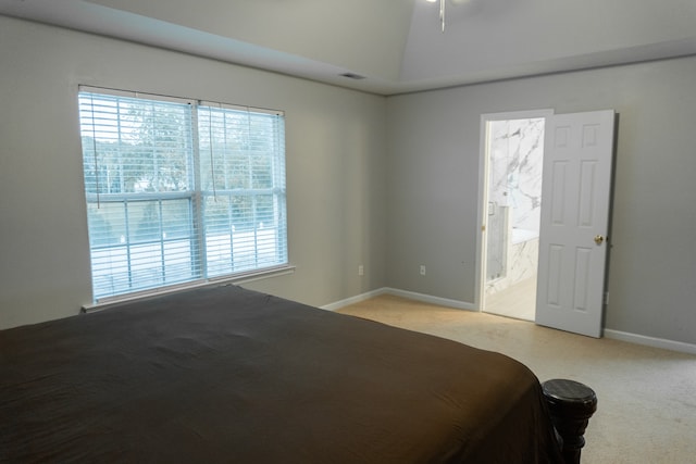 unfurnished bedroom featuring connected bathroom, vaulted ceiling, and light carpet