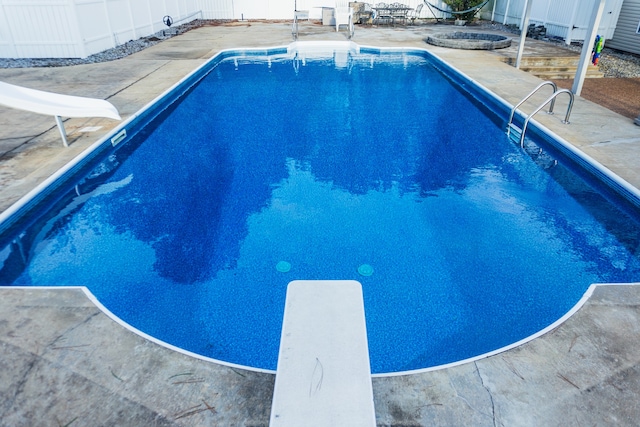 view of pool featuring a patio area, a water slide, and a diving board