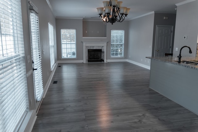 unfurnished living room with sink, ornamental molding, dark hardwood / wood-style flooring, and a high end fireplace