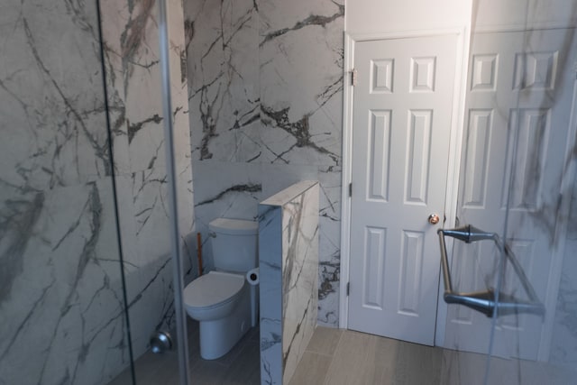 bathroom with toilet and tile walls