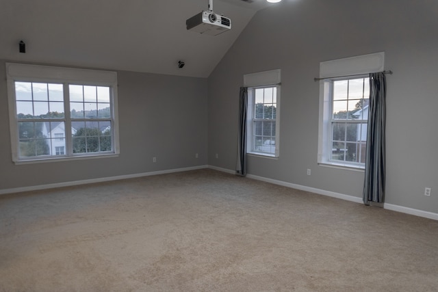 spare room featuring lofted ceiling and light colored carpet