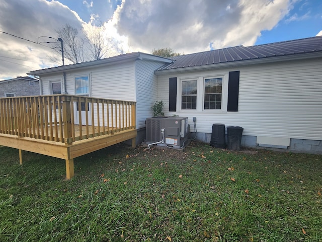 back of property featuring a wooden deck, central air condition unit, and a lawn