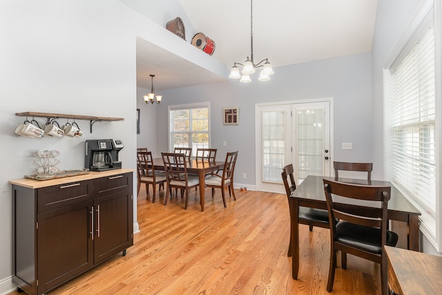 dining room featuring light hardwood / wood-style flooring, vaulted ceiling, and an inviting chandelier