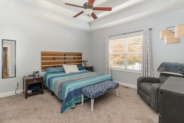 bedroom featuring light colored carpet, a tray ceiling, and ceiling fan