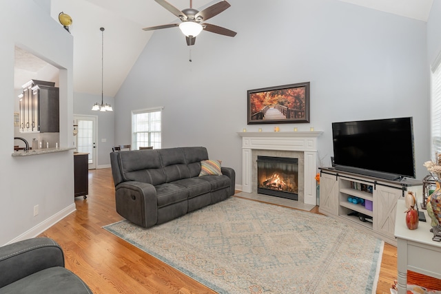 living room with high vaulted ceiling, light hardwood / wood-style flooring, and ceiling fan with notable chandelier