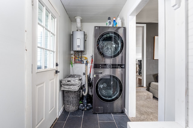 washroom with water heater, dark tile patterned floors, and stacked washer and clothes dryer