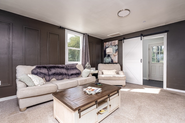 living room with a barn door, light colored carpet, and plenty of natural light