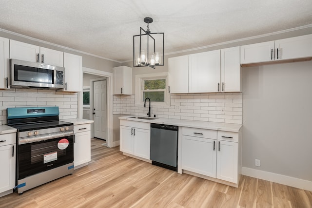 kitchen featuring hanging light fixtures, appliances with stainless steel finishes, white cabinetry, light wood-type flooring, and sink