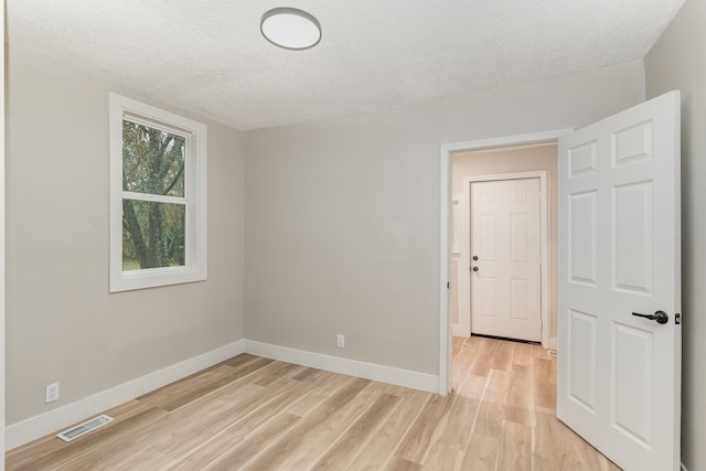 unfurnished room with a textured ceiling and light hardwood / wood-style flooring