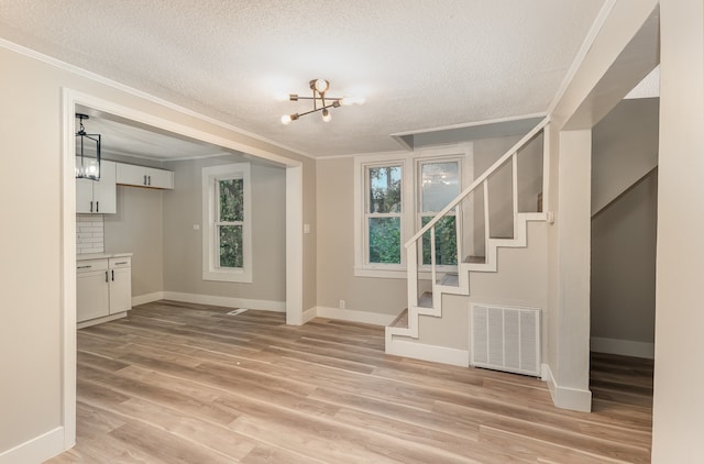 interior space featuring ornamental molding, light hardwood / wood-style flooring, and a textured ceiling