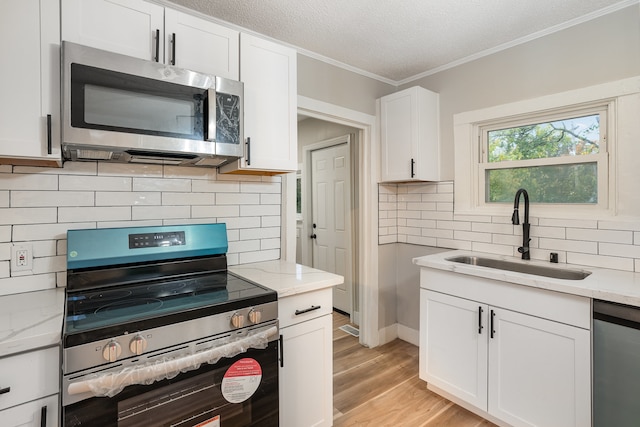 kitchen with light stone countertops, sink, appliances with stainless steel finishes, and white cabinets