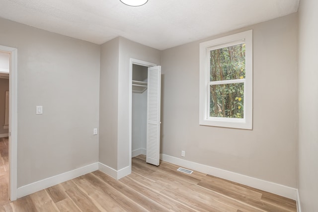 unfurnished bedroom with a closet, a textured ceiling, and light hardwood / wood-style floors