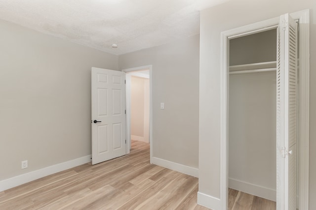 unfurnished bedroom with a closet, light hardwood / wood-style floors, and a textured ceiling