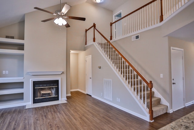 unfurnished living room featuring ceiling fan, high vaulted ceiling, dark hardwood / wood-style flooring, and built in shelves