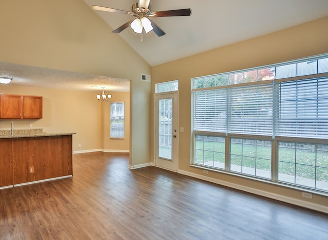 unfurnished living room featuring a textured ceiling, high vaulted ceiling, dark wood-type flooring, ceiling fan with notable chandelier, and sink