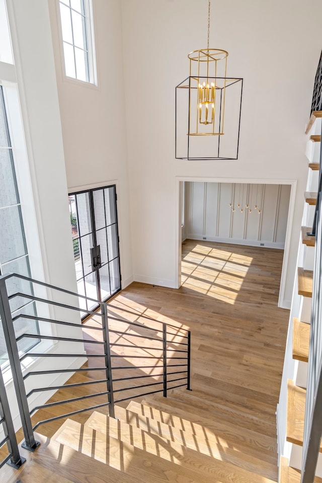 interior space featuring a towering ceiling, a notable chandelier, and light hardwood / wood-style flooring