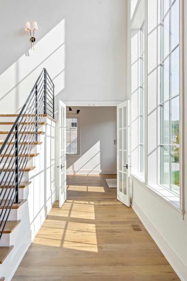 interior space with hardwood / wood-style floors, a towering ceiling, and french doors