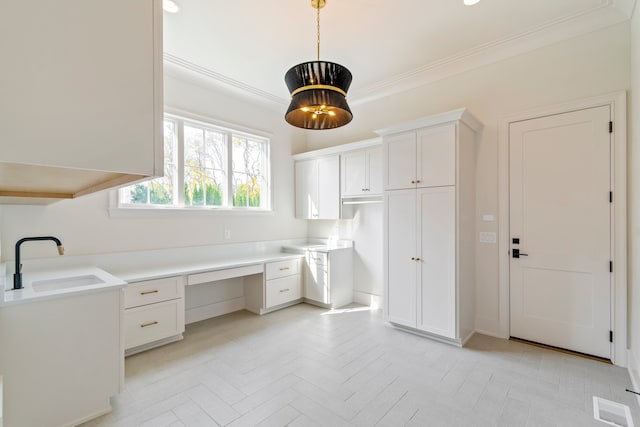 interior space featuring ornamental molding, built in desk, sink, and light parquet floors