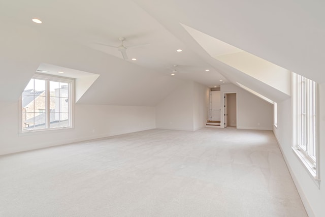 additional living space with vaulted ceiling, light colored carpet, and ceiling fan