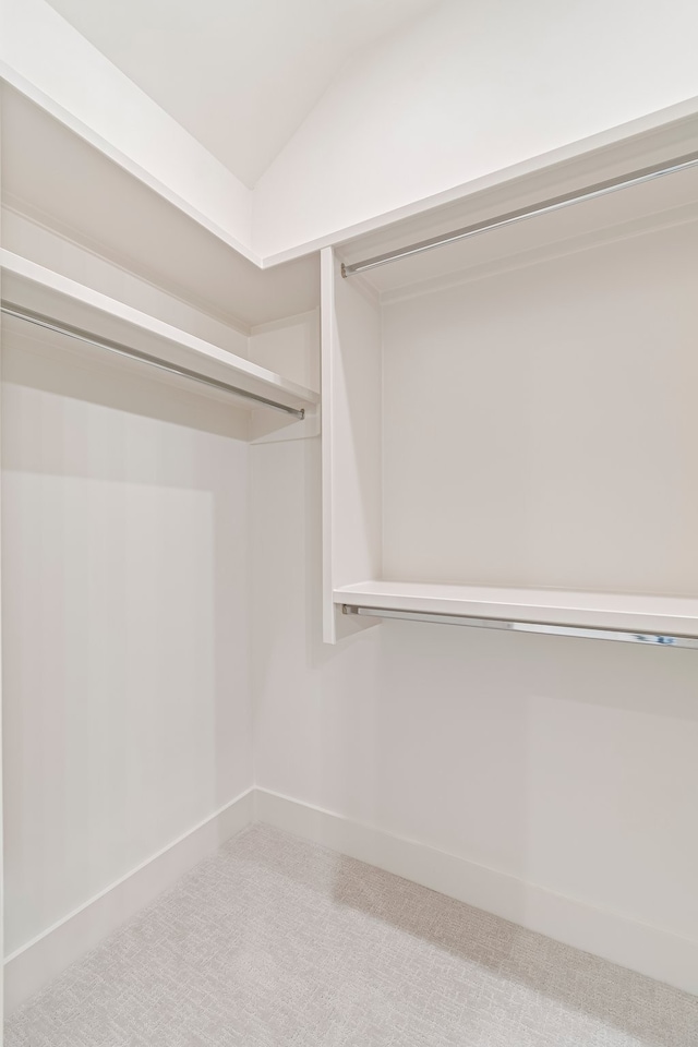 walk in closet with carpet and lofted ceiling