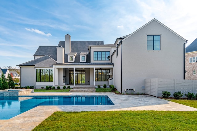 back of house with a swimming pool with hot tub, a patio, and a lawn