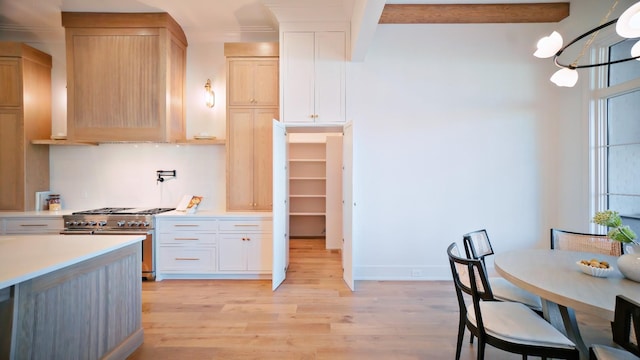 kitchen with light brown cabinetry, high end stove, white cabinets, light hardwood / wood-style floors, and beam ceiling