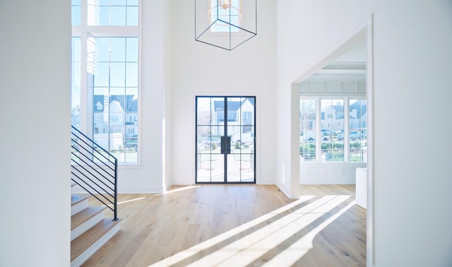 entrance foyer with a towering ceiling and light hardwood / wood-style floors