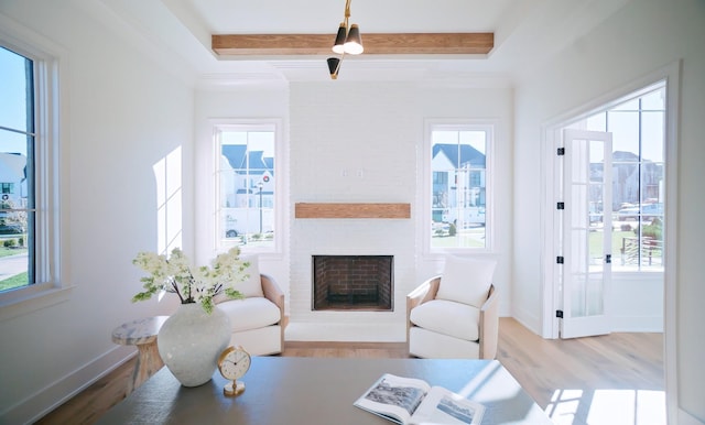 living room with a brick fireplace, beam ceiling, and light hardwood / wood-style floors