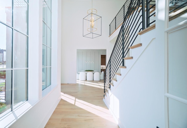 staircase featuring wood-type flooring, a chandelier, and a high ceiling