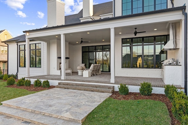 property entrance featuring an outdoor kitchen, ceiling fan, a patio, and a lawn