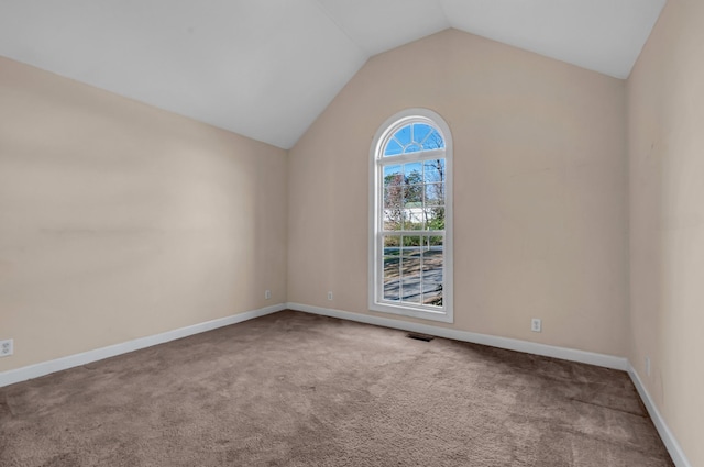 carpeted spare room with vaulted ceiling