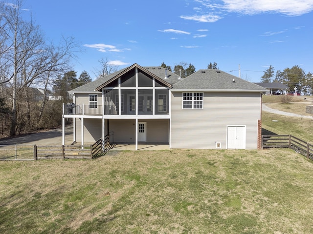 rear view of house featuring roof with shingles, a fenced backyard, a sunroom, a patio area, and a lawn
