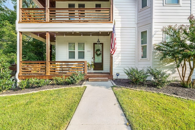 doorway to property with a balcony and a lawn