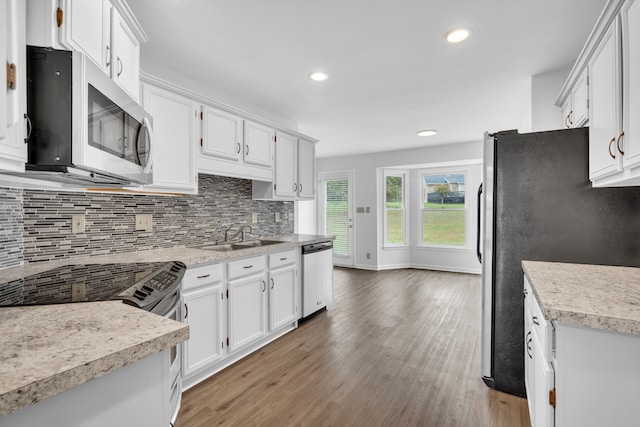 kitchen with backsplash, white cabinetry, hardwood / wood-style flooring, sink, and stainless steel appliances