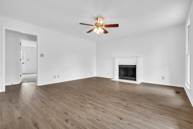 unfurnished living room featuring dark wood-type flooring and ceiling fan