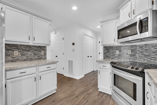 kitchen with white cabinetry, light stone counters, appliances with stainless steel finishes, and dark hardwood / wood-style floors