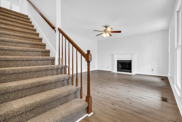 stairway with hardwood / wood-style floors and ceiling fan