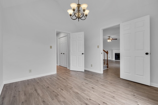 spare room with light hardwood / wood-style flooring, high vaulted ceiling, and ceiling fan with notable chandelier