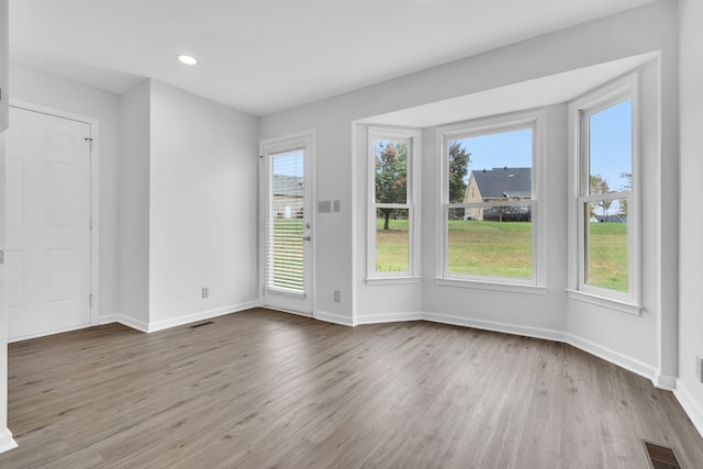 empty room with hardwood / wood-style floors and a healthy amount of sunlight