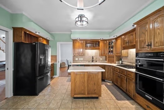 kitchen with decorative backsplash, a kitchen island, sink, black appliances, and light tile patterned floors