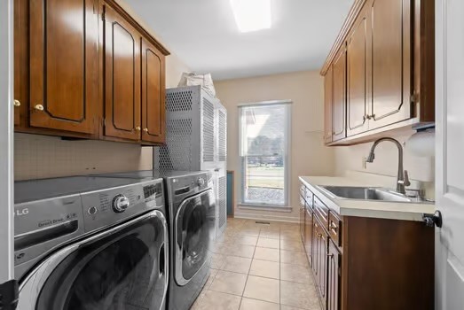 washroom with light tile patterned floors, cabinets, sink, and independent washer and dryer