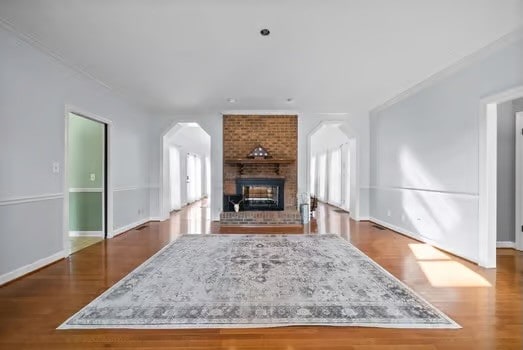 living room featuring plenty of natural light, ornamental molding, a brick fireplace, and dark hardwood / wood-style floors