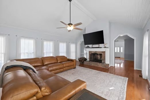 living room with vaulted ceiling with beams, a brick fireplace, ceiling fan, and light hardwood / wood-style floors