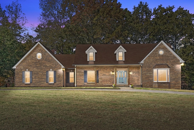 cape cod home featuring a lawn