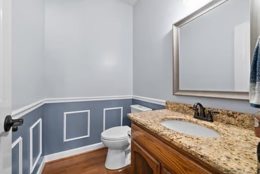 bathroom with vanity, toilet, and hardwood / wood-style flooring