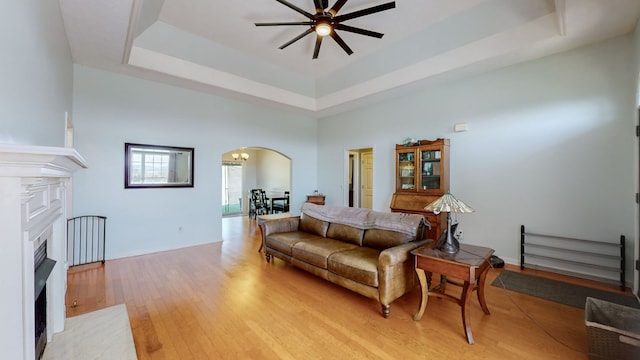 living room featuring ceiling fan, light wood-type flooring, and a raised ceiling