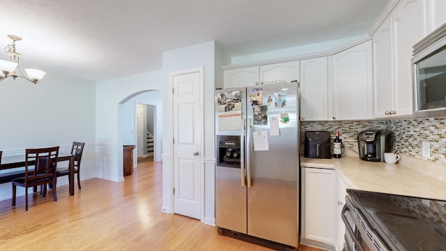 kitchen featuring appliances with stainless steel finishes, light wood-type flooring, a textured ceiling, white cabinetry, and pendant lighting