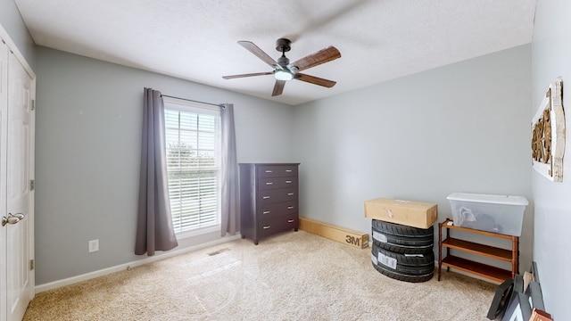 bedroom featuring ceiling fan, a textured ceiling, and light colored carpet