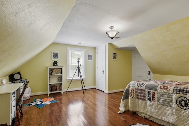 bedroom featuring a textured ceiling, wood-type flooring, and vaulted ceiling